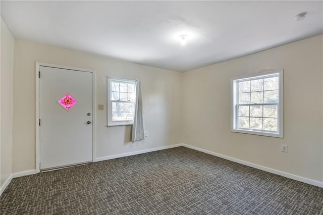 unfurnished room with plenty of natural light and dark colored carpet