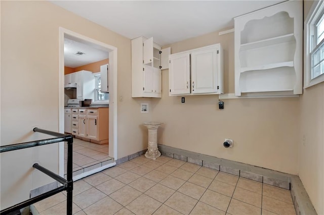 clothes washing area with hookup for an electric dryer, light tile patterned floors, a healthy amount of sunlight, and washer hookup