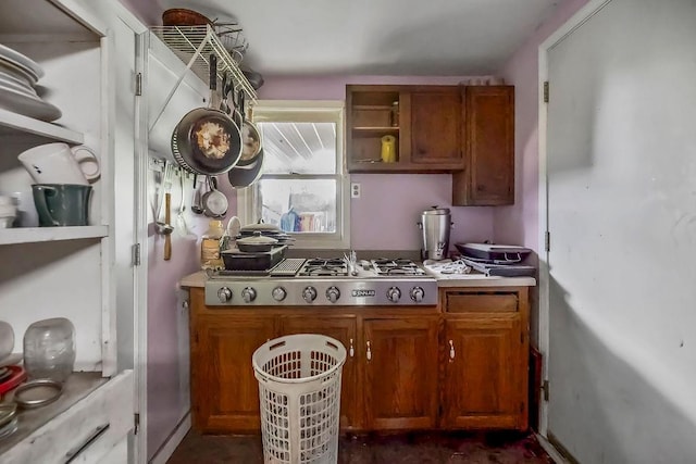 kitchen featuring stainless steel gas cooktop, brown cabinets, open shelves, and light countertops