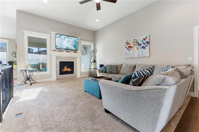 living room with ceiling fan, carpet flooring, a wealth of natural light, and a fireplace