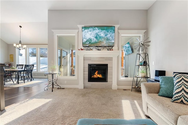 living room with a fireplace, a notable chandelier, carpet floors, and vaulted ceiling