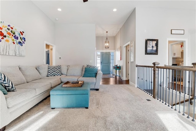 carpeted living room featuring a towering ceiling