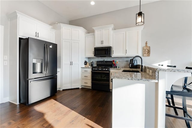 kitchen featuring black appliances, white cabinetry, sink, light stone counters, and kitchen peninsula