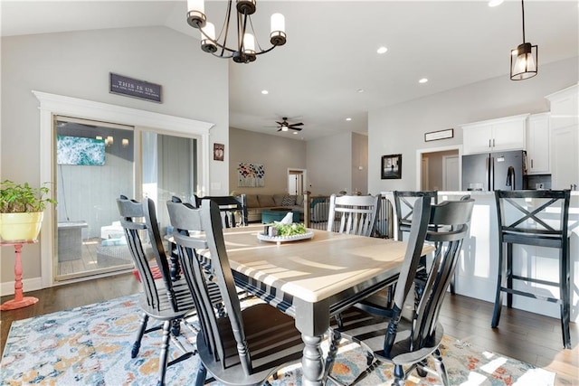 dining space with ceiling fan with notable chandelier, vaulted ceiling, and dark hardwood / wood-style floors