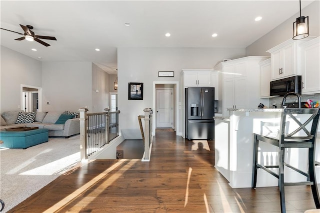 kitchen featuring dark hardwood / wood-style floors, white cabinets, a kitchen breakfast bar, hanging light fixtures, and fridge with ice dispenser