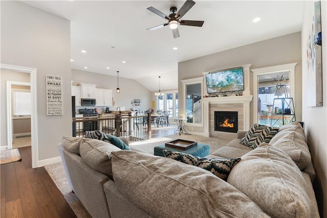 living room featuring a tiled fireplace, lofted ceiling, hardwood / wood-style flooring, and ceiling fan