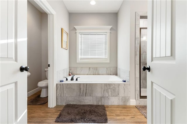 bathroom featuring toilet, hardwood / wood-style floors, and shower with separate bathtub