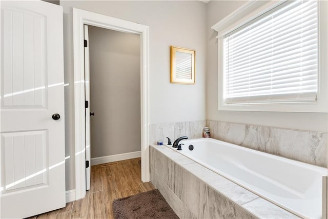 bathroom featuring a relaxing tiled tub and hardwood / wood-style flooring