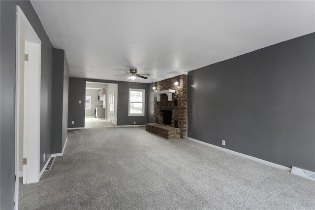 unfurnished living room with a brick fireplace, ceiling fan, and carpet flooring