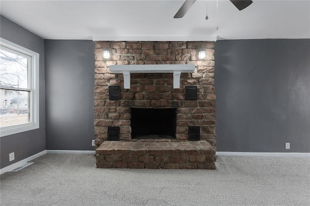 carpeted living room with ceiling fan and a stone fireplace