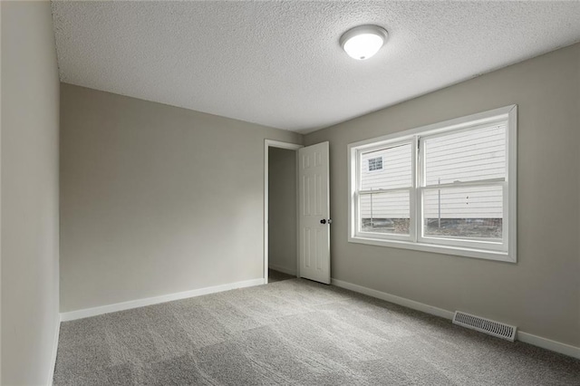 unfurnished room with a textured ceiling and carpet