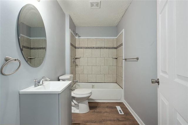 full bathroom featuring toilet, hardwood / wood-style flooring, a textured ceiling, tiled shower / bath, and vanity