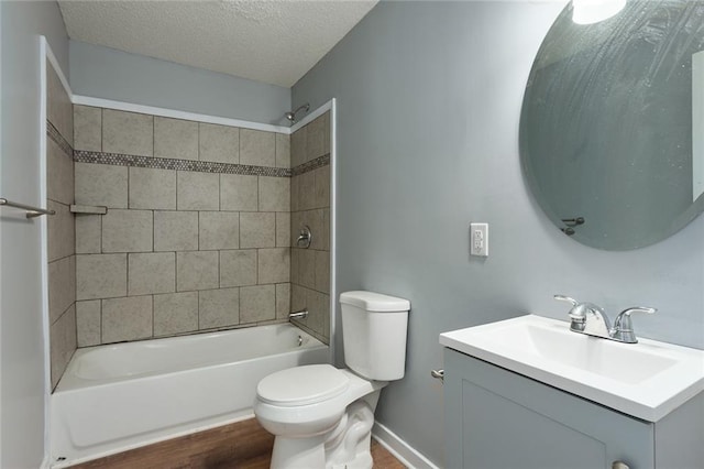 full bathroom featuring hardwood / wood-style floors, tiled shower / bath combo, toilet, vanity, and a textured ceiling