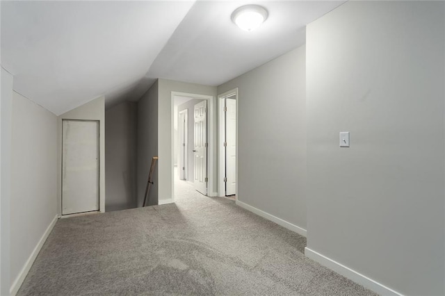 hall featuring lofted ceiling and light carpet