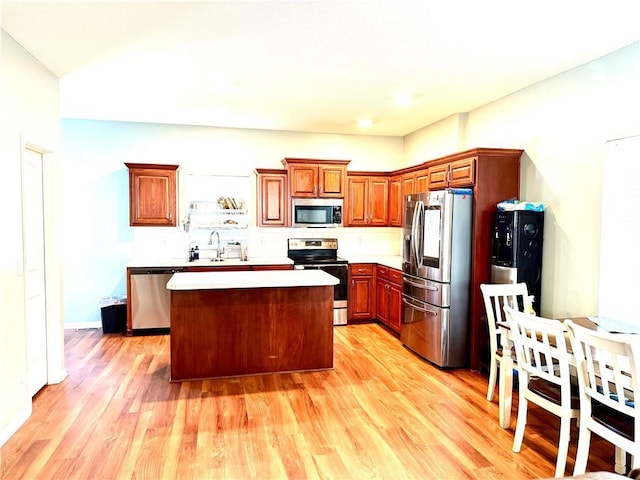 kitchen featuring appliances with stainless steel finishes, light wood-type flooring, sink, and a kitchen island