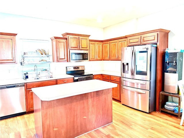 kitchen featuring stainless steel appliances, sink, a center island, and light wood-type flooring