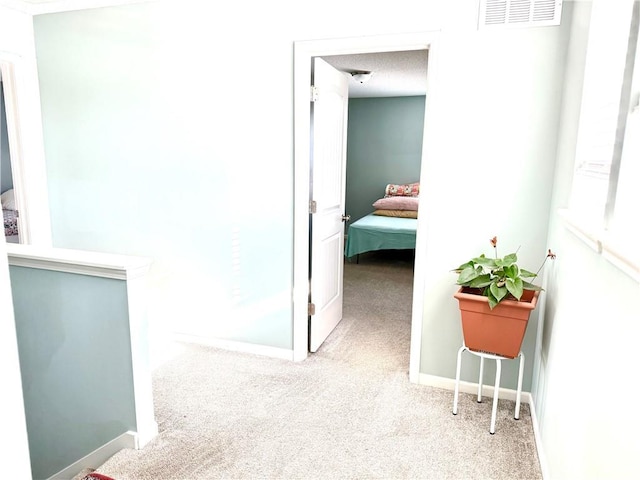 hall featuring a textured ceiling and light carpet