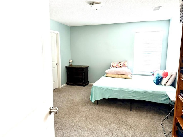 bedroom with light colored carpet and a textured ceiling