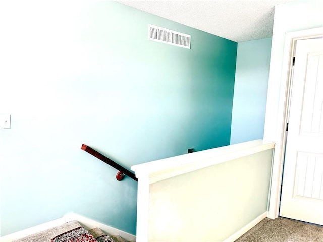 stairs featuring a textured ceiling and carpet flooring