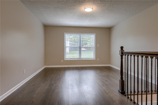 empty room featuring a textured ceiling and dark wood-type flooring