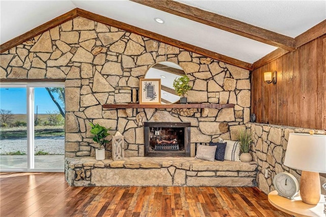 unfurnished living room featuring a wealth of natural light, wooden walls, vaulted ceiling with beams, and a fireplace