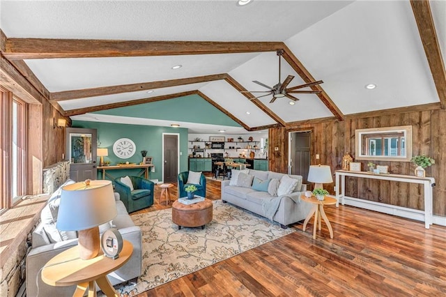 living room featuring a baseboard radiator, lofted ceiling with beams, wood walls, hardwood / wood-style floors, and ceiling fan