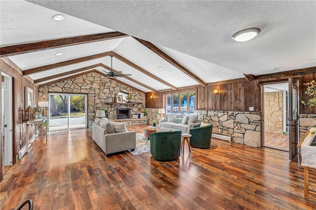 living room with a textured ceiling, lofted ceiling with beams, dark hardwood / wood-style flooring, a fireplace, and ceiling fan