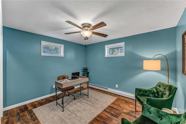 office space featuring a wealth of natural light, dark hardwood / wood-style floors, and a baseboard heating unit