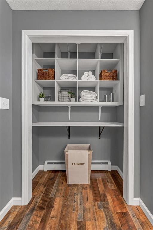 interior details with a textured ceiling, a baseboard heating unit, and hardwood / wood-style flooring