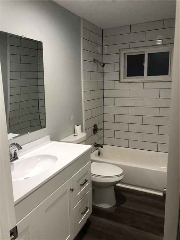 full bathroom featuring toilet, hardwood / wood-style flooring, tiled shower / bath combo, and vanity