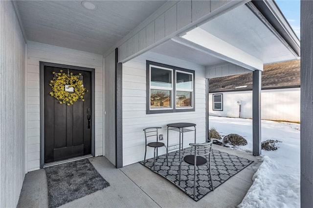 snow covered property entrance featuring a porch