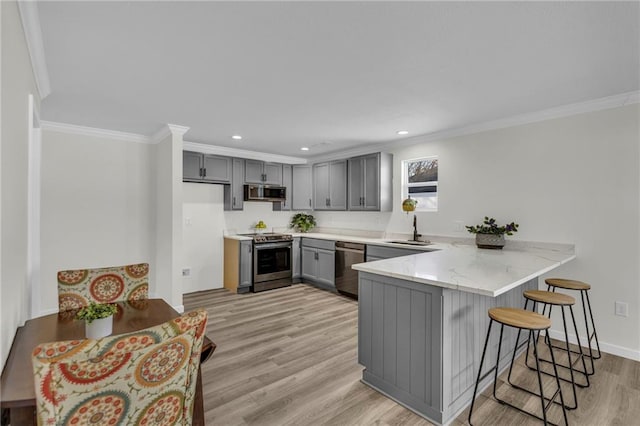 kitchen featuring kitchen peninsula, stainless steel appliances, gray cabinetry, ornamental molding, and sink