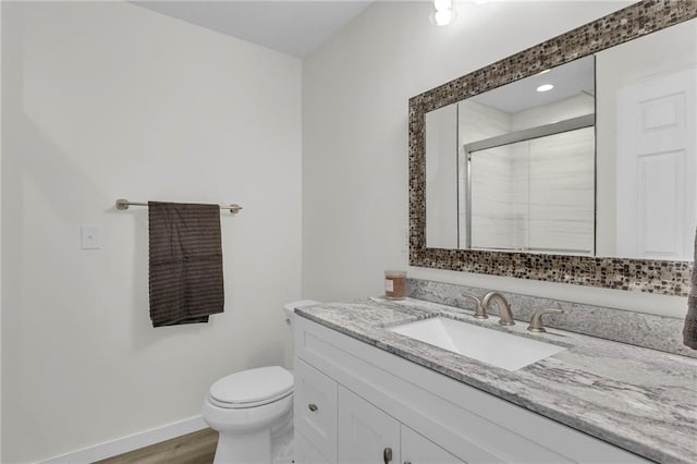 bathroom featuring toilet, hardwood / wood-style flooring, a shower with door, and vanity