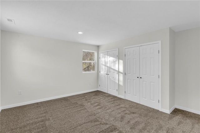 unfurnished bedroom featuring carpet floors and two closets