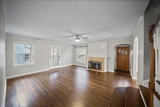 unfurnished living room with ceiling fan, dark wood-type flooring, crown molding, and a textured ceiling