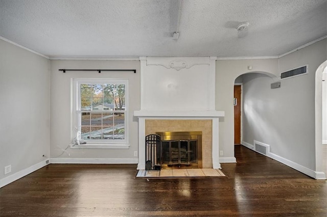 unfurnished living room with a tile fireplace, a textured ceiling, crown molding, and dark hardwood / wood-style floors