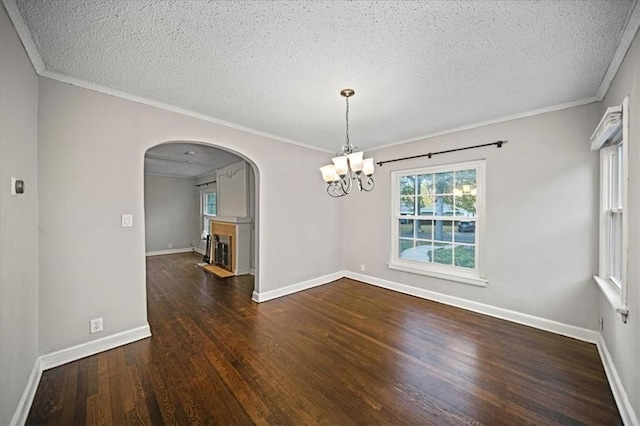 unfurnished dining area with dark hardwood / wood-style flooring, a textured ceiling, a notable chandelier, and crown molding