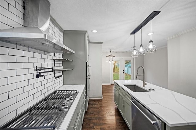 kitchen featuring wall chimney exhaust hood, tasteful backsplash, gray cabinets, appliances with stainless steel finishes, and sink