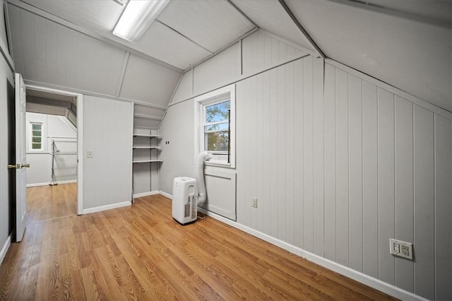 interior space with vaulted ceiling, light hardwood / wood-style flooring, and wooden walls