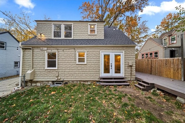 rear view of property with french doors, a wooden deck, and a yard