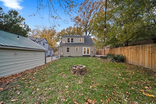 back of property featuring an outdoor fire pit and a lawn