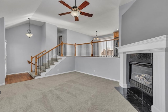 unfurnished living room featuring lofted ceiling, a tiled fireplace, ceiling fan, and dark carpet