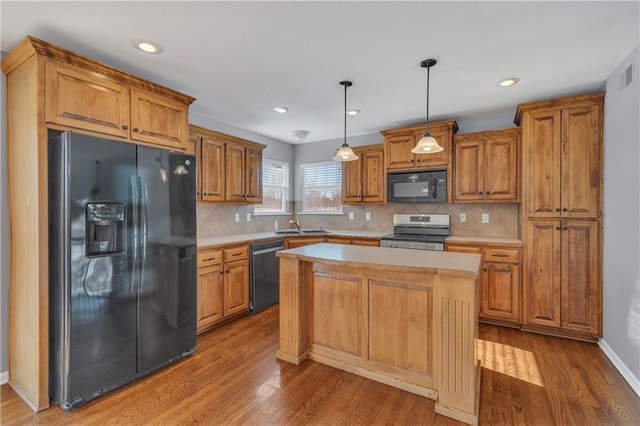 kitchen featuring decorative light fixtures, tasteful backsplash, wood-type flooring, a kitchen island, and black appliances