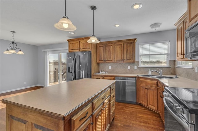 kitchen with a kitchen island, black appliances, pendant lighting, and sink