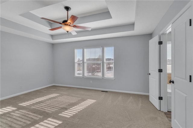 carpeted spare room featuring ceiling fan and a tray ceiling