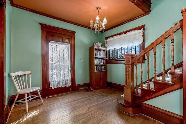 unfurnished room featuring hardwood / wood-style flooring, ornamental molding, and a notable chandelier