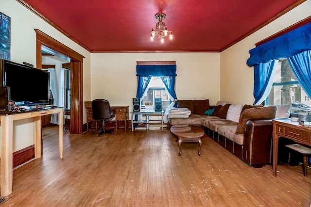 living room with ornamental molding, a notable chandelier, and light hardwood / wood-style flooring