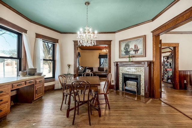 dining room featuring a tiled fireplace, dark wood-type flooring, ornamental molding, and an inviting chandelier