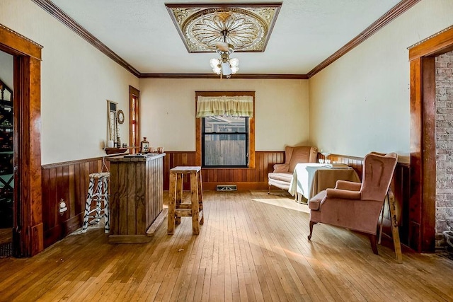 sitting room with a notable chandelier, ornamental molding, and light hardwood / wood-style floors