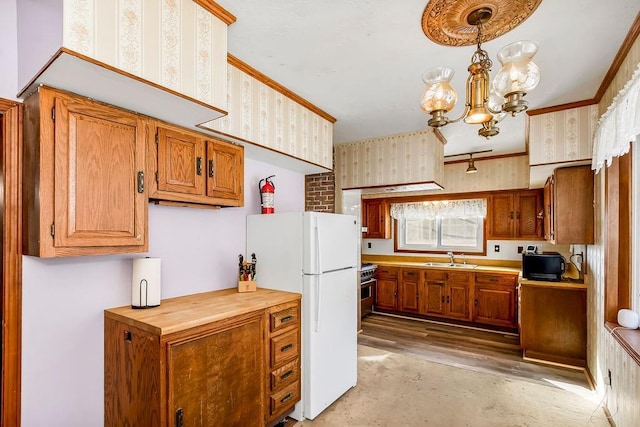 kitchen featuring pendant lighting, sink, concrete floors, white refrigerator, and an inviting chandelier